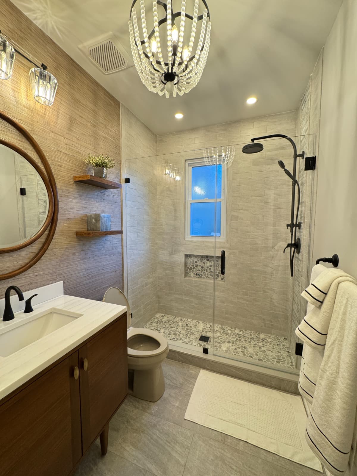 Finished tile bathroom with a tiled shower, pebble floor and wood-look wall tile